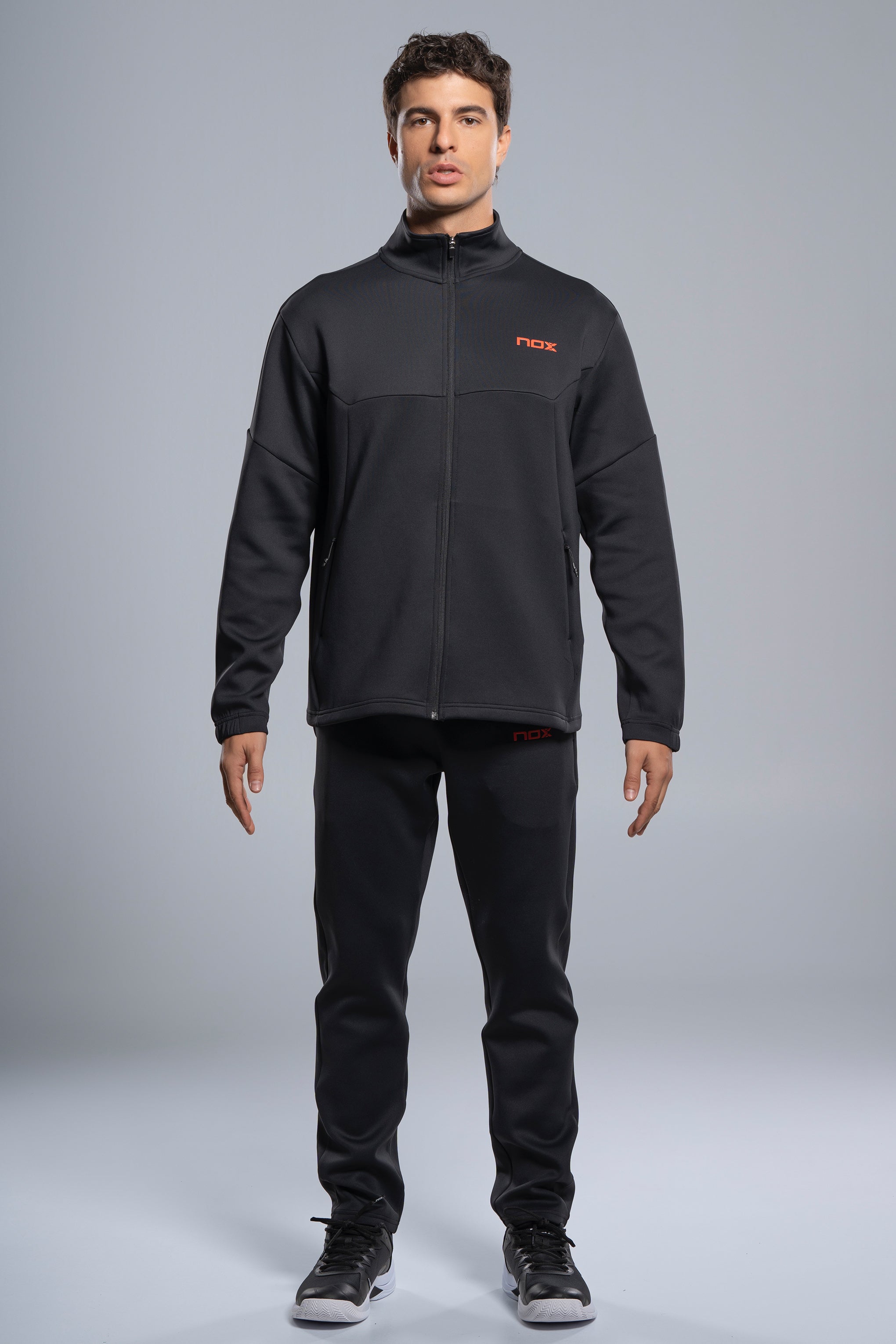 Jugador de pádel usando la chaqueta técnica Nox Team negra